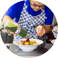 guy with apron pouring sauce image